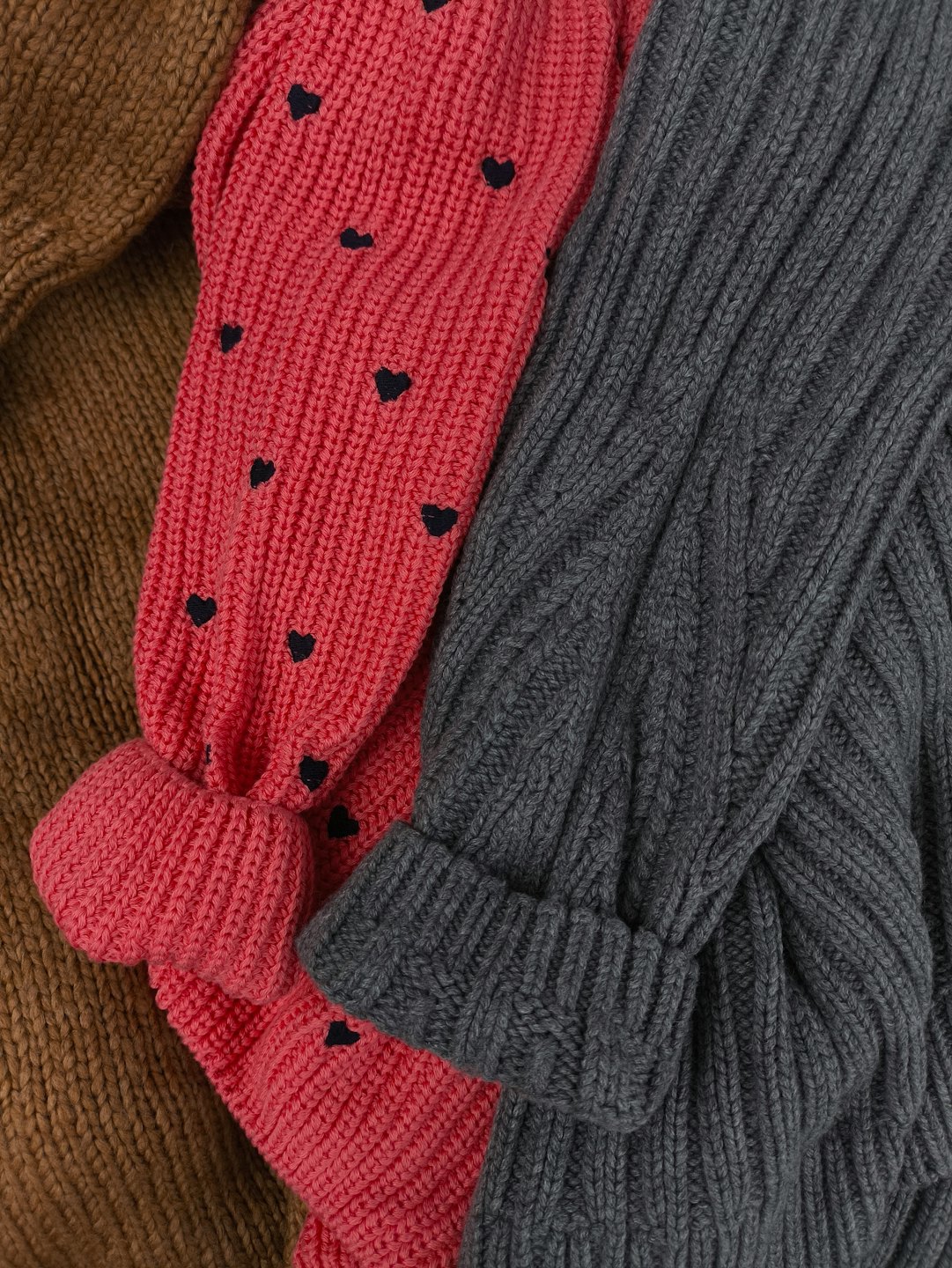 Three cozy knitted sweaters in different textures and colors.