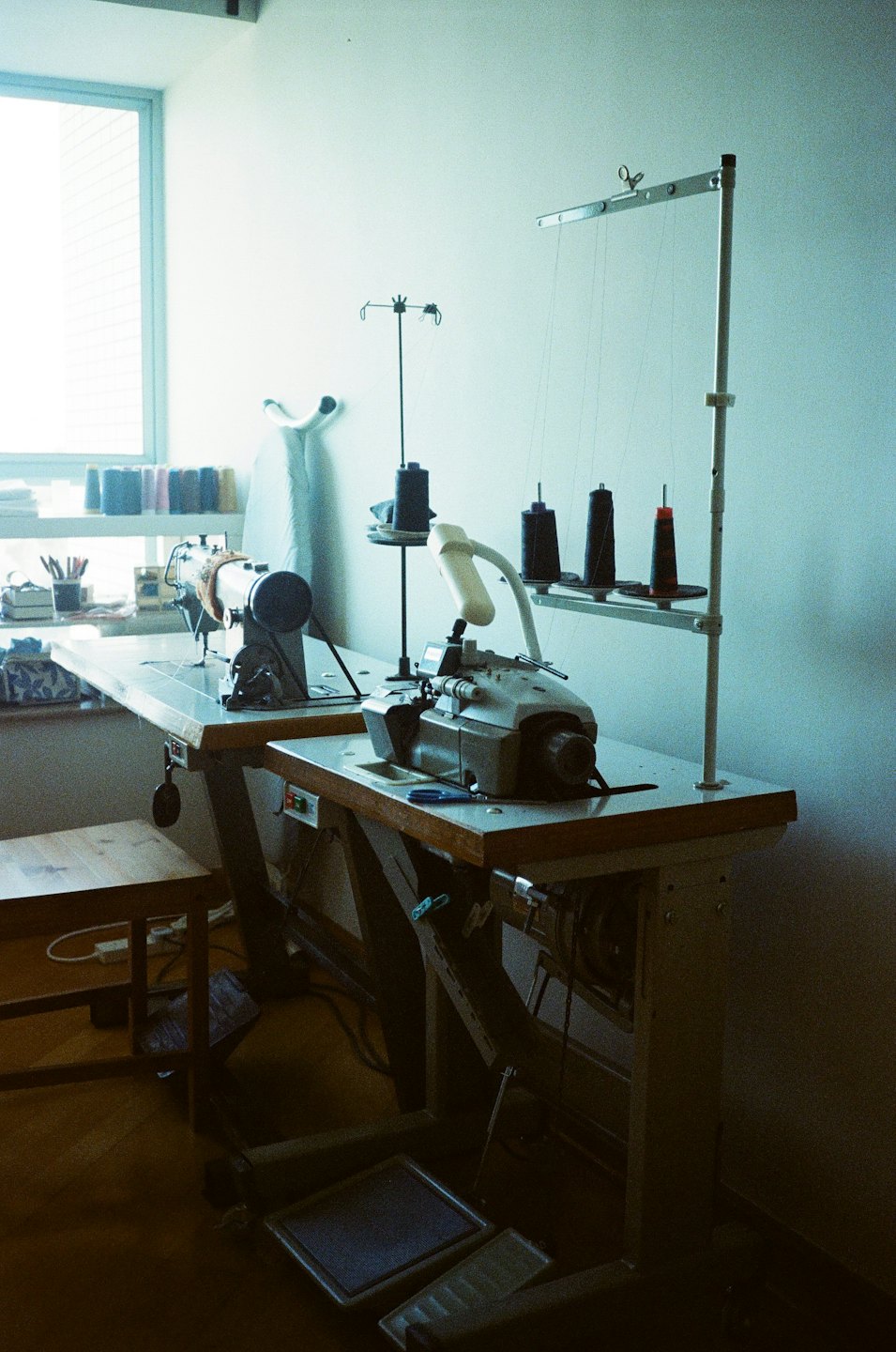 Two industrial sewing machines ready for use in a bright workshop.