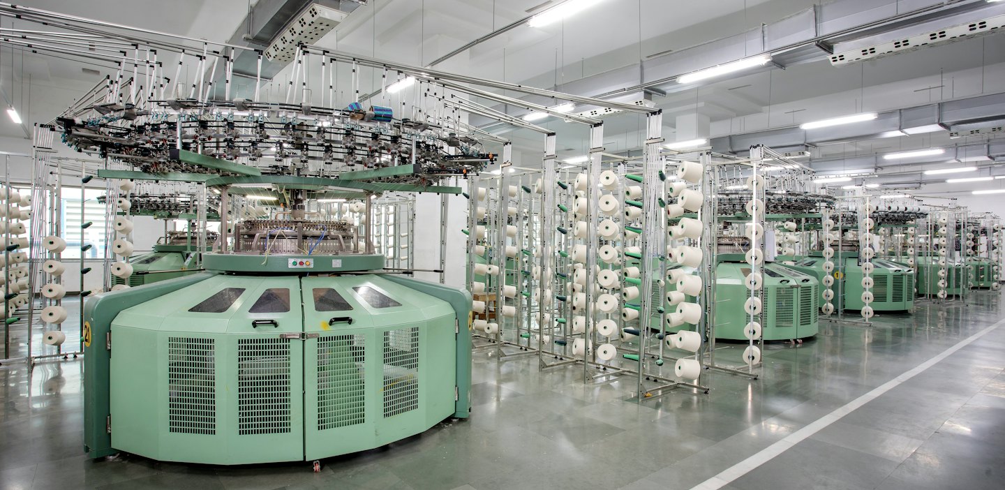 Light green knitting machines in a factory production line.