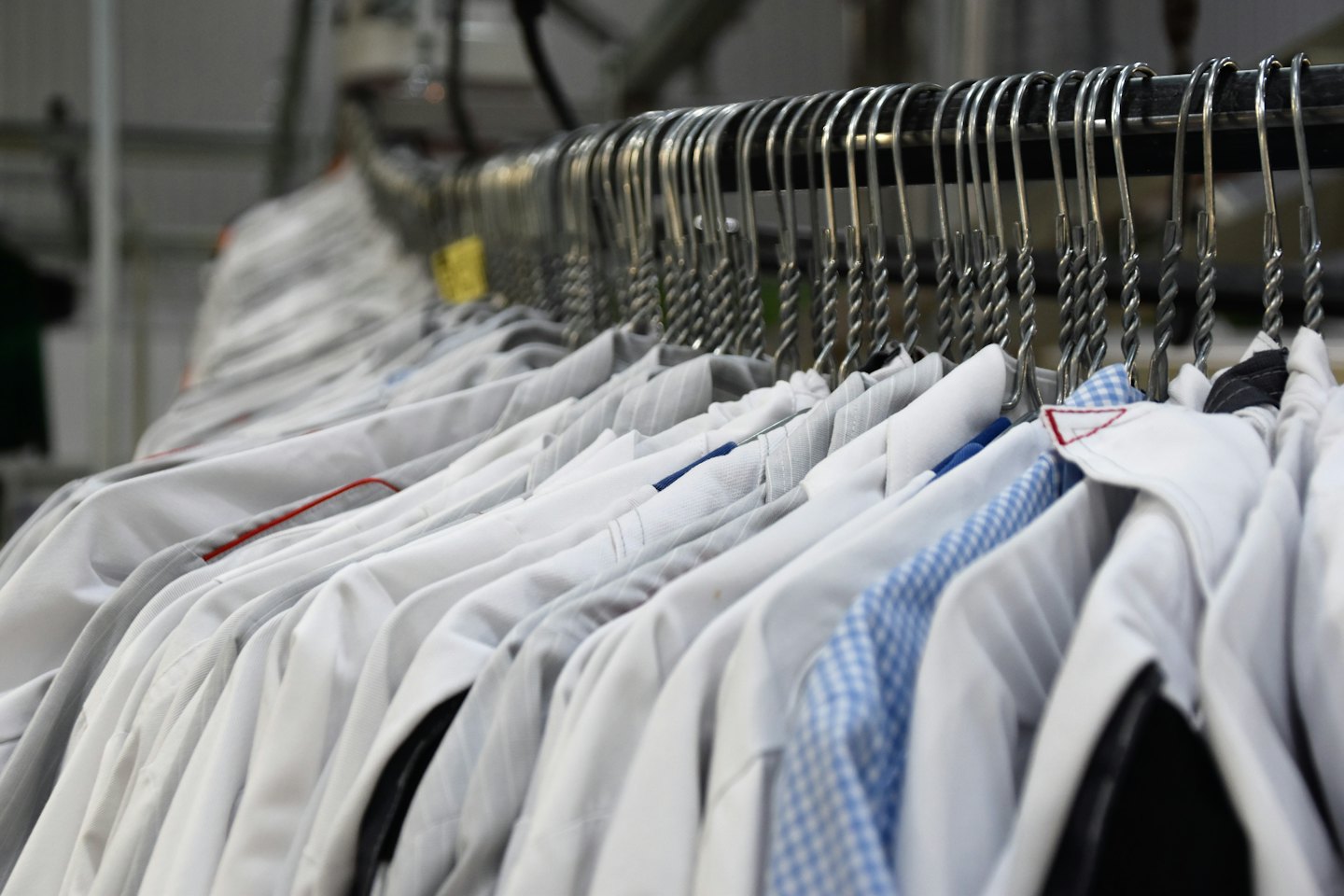 Rows of uniform shirts hanging on metal hangers.